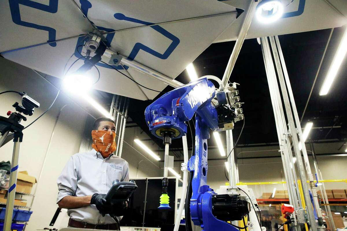 Zohair Naqui checks the positioning of lights over a machine as Plus One Robotics employees work on tuning operations of warehouse robots on April 16, 2020.