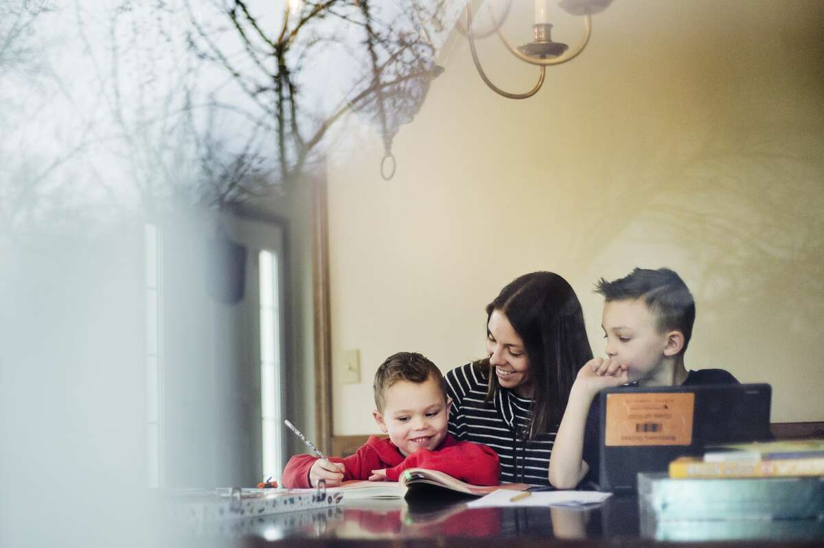 Elizabeth Matthews poses for a portrait with her sons, Colton, 8, right, and Levi, 6, left, Tuesday, March 31, 2020 at their home in Midland. "This past month has been an adjustment for all of us. Our new "normal" is school taking place around our dining room table. Some days go smoother than others, but we are trying to make the best out of the situation and enjoy the extra time together," Elizabeth said. (Katy Kildee/kkildee@mdn.net)