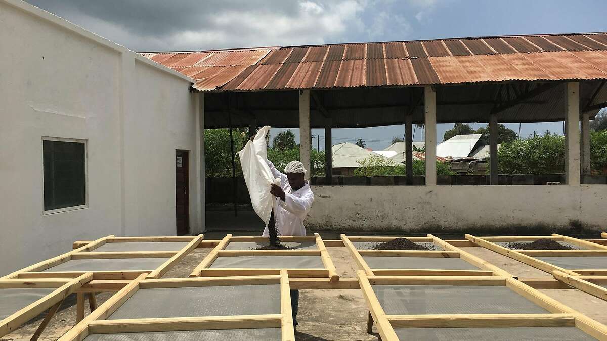 A farmer loads black peppercorns on a drying tray in Tanzania. The pepper will get shipped to Burlap & Barrel, a single-origin spice company with roots in San Francisco.