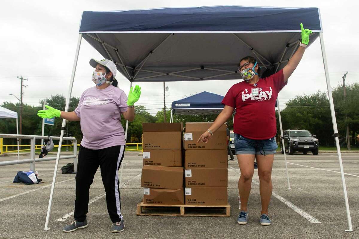 Elizabeth Lopez, left, and Sandra Rodriguez, right, dance while waiting for vehicles to line up during the April 17, 2020 San Antonio Food Bank distribution at the Alamodome in San Antonio, Texas. About 2,200 families were pre-registered to receive food at the distribution