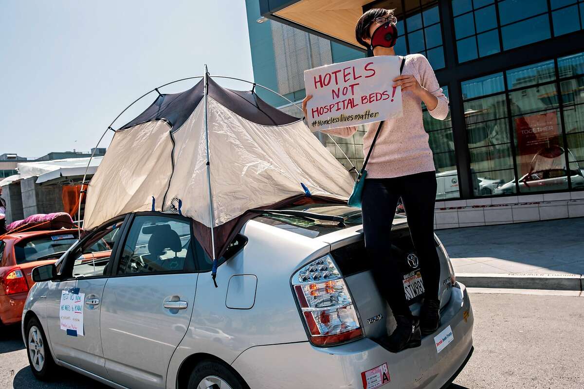 2020年4月13日，星期一，在加利福尼亚州旧金山，抗议者艾米丽·李站在车上举着一个牌子，此前约50人的车队驶过莫斯科尼中心，要求为无家可归者提供住所。