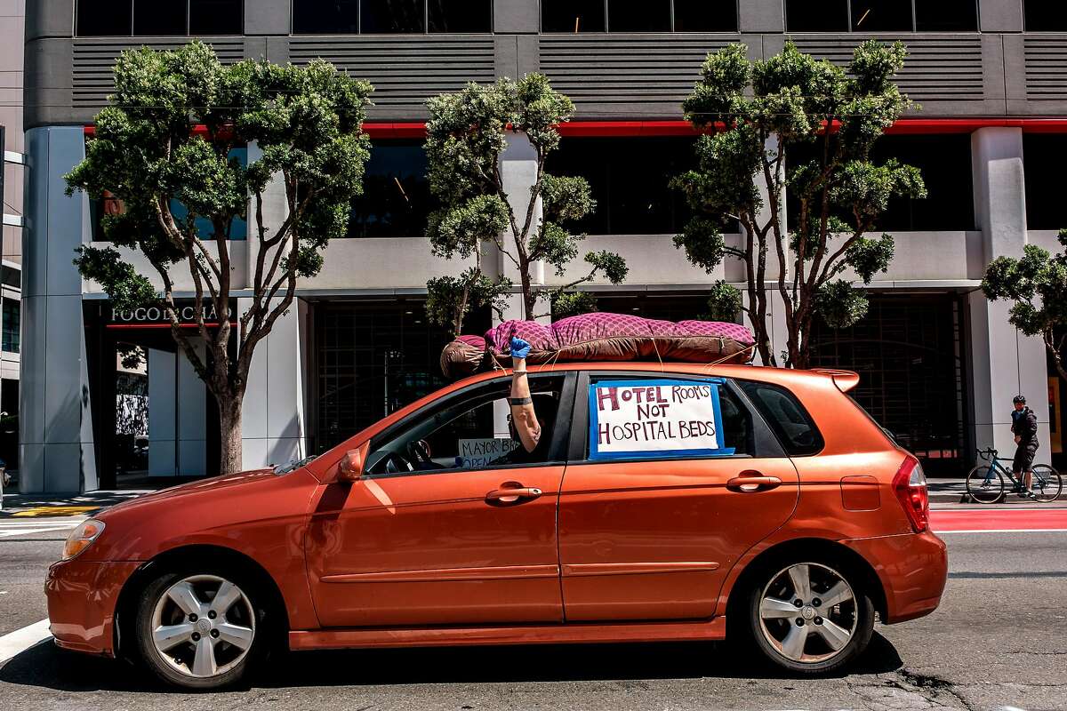A protester is seen in the car as a car convoy of about 50 drives by the Moscone Center to demand shelter for the homeless in San Francisco, Calif. on Monday April 13, 2020.