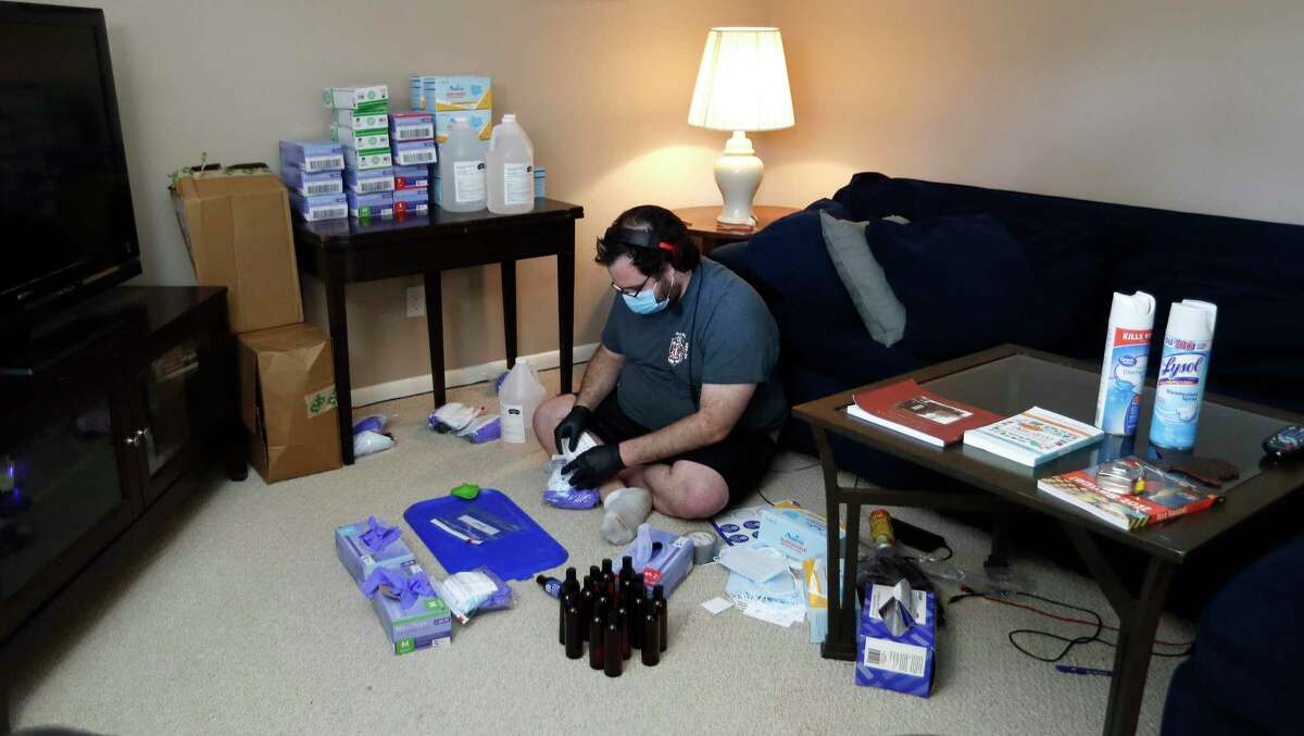 Matthew Marchetti with CrowdSource Rescue, places PPE in bags for those in need of personal protection equipment in his living room, in Houston,Friday, April 17, 2020. During disasters, CrowdSource Resource hooks up people in trouble to volunteers who can help. "We're a bunch of tech nerds and response cowboys -- people with chainsaws and boats," says Matthew Marchetti, one of the guys who accidentally started the group during Hurricane Harvey. A pandemic wasn't their sort of crisis. Then they realized that people vulnerable to the coronavirus were going to need food, and nobody was there to deliver it.
