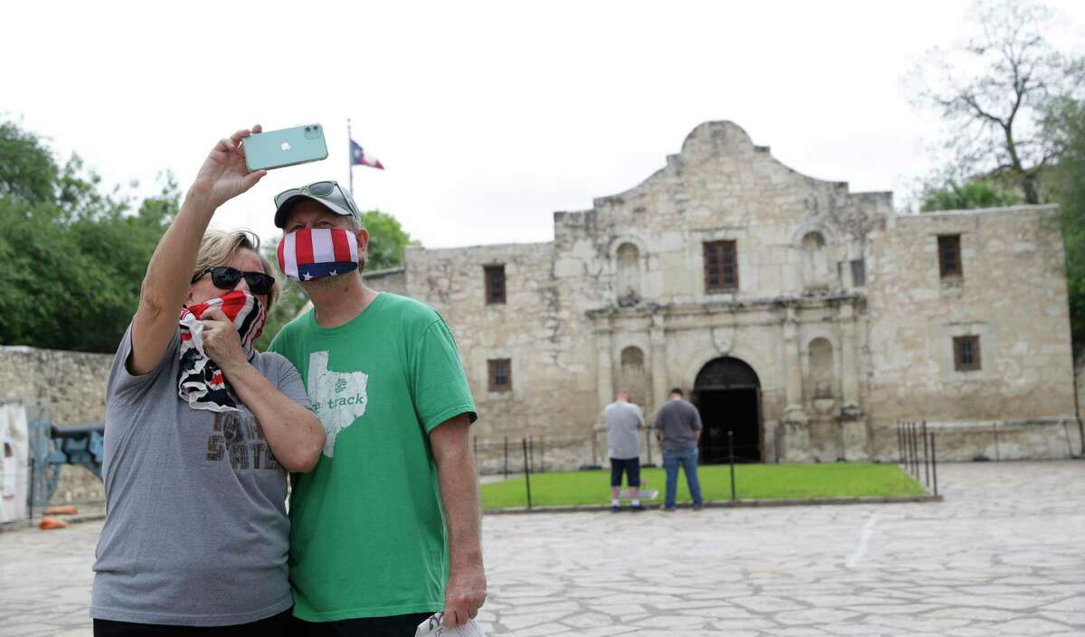 Visitors wear face masks as they take a selfie in front of the Alamo on April 10. The Alamo chapel remains closed due to the COVID-19 outbreak but the grounds and gift shop are open for the first time since the Texas iconic site was closed five months ago because of the virus.