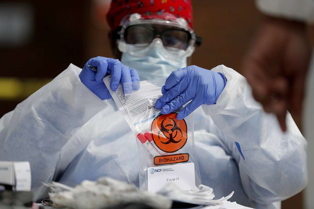 Registered medical assistant Elaine Lomax handles a nasal swab specimen after it was collected at a drive-thru COVID-19 testing site Thursday, April 16, 2020, in St. Louis. (AP Photo/Jeff Roberson)