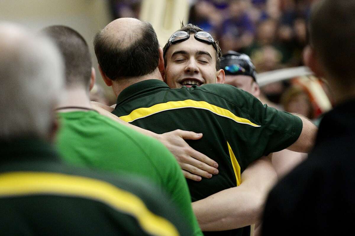 Dow High's Nehemiah Mork hugs Chargers' coach Chilly Smith after winning the 100-yard freestyle at the Division 2 state finals on March 12, 2016 at SVSU.