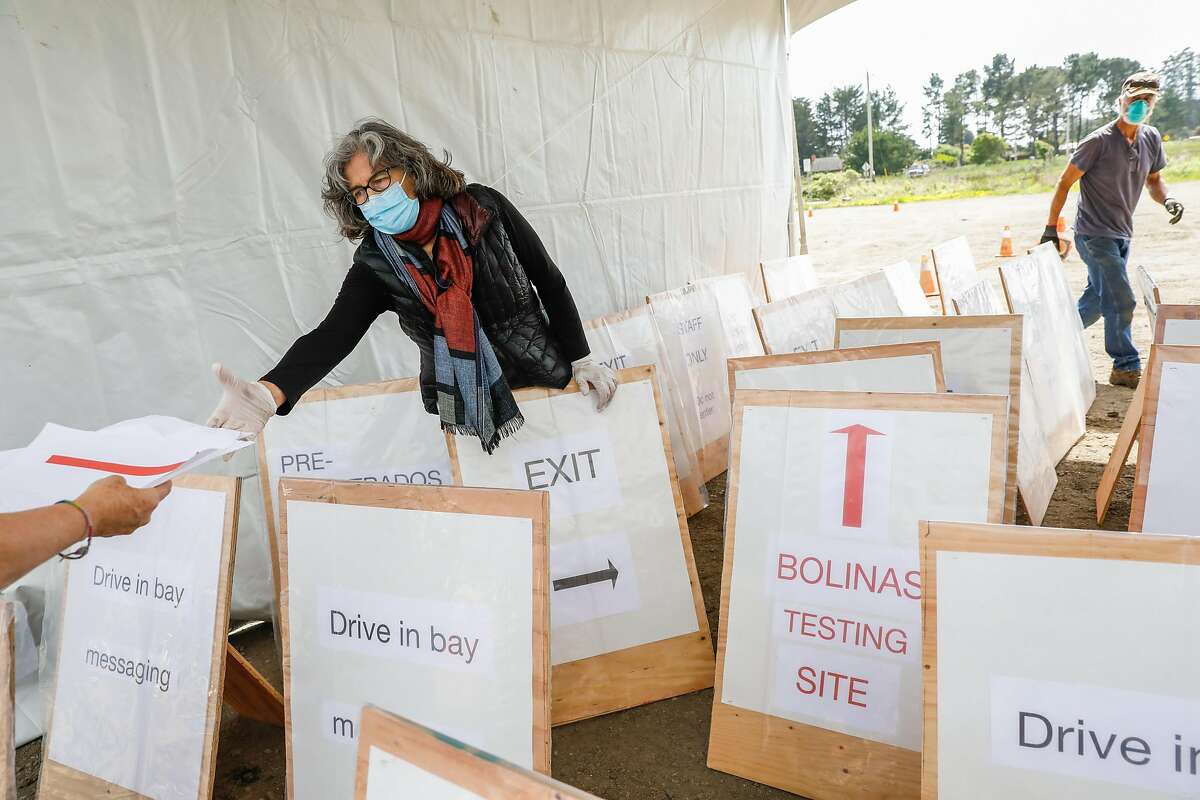 Aenor Sawyer (left) helps to unload signage while setting up a testing site for people to get their blood tested for covid-19 in Bolinas, California on Sunday, April 19, 2020.