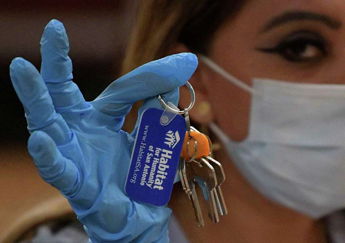 Aida Nambo, 24, displays the keys to her family's new Habitat for Humanity home on Wednesday, April 15, 2020. The organization's house dedication ceremonies are now being done on video due to the coronavirus pandemic, and people doing business with the organization must wear face masks.