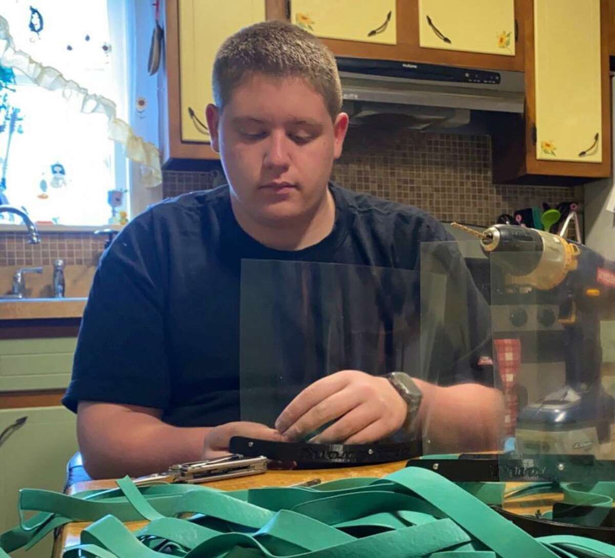 Shelton High sophomore Josh Mallette assembling a plastic face shield that he created with his 3D printer. He is donating the face shields he creates to area medical facilities.