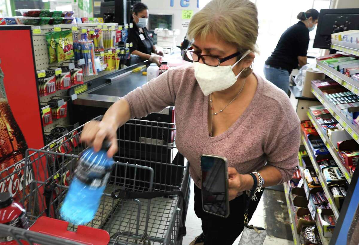 Lydia Segura, a shoppers at La Fiesta on S. Flores, wears a mask as she unloads her purchases so cashier Yvonne Acevedo, left, can check her out on April 20, 2020. Gov. Greg Abbott on Monday issued a new executive order overriding COVID-19 restrictions enacted by San Antonio, Bexar County and other local governments — including the requirement that people wear facial coverings in public in situations where maintaining a 6-foot distance from others would be difficult.