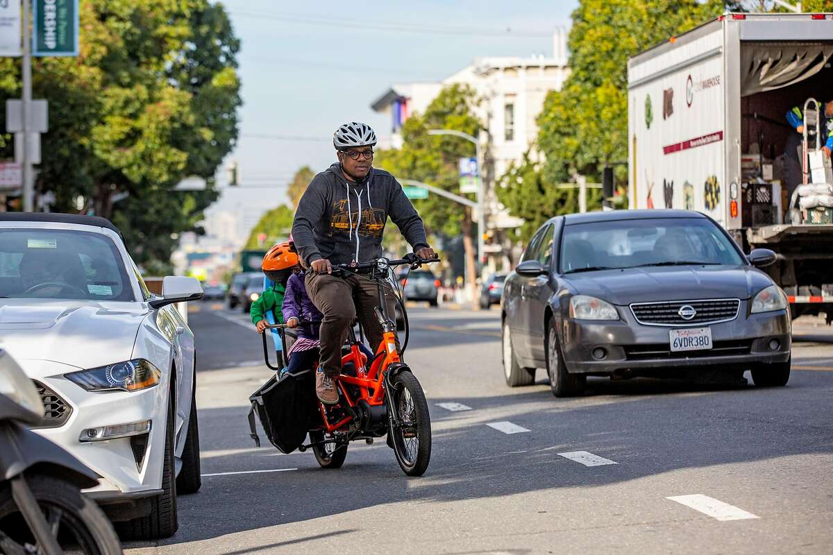 Ed Parillon with his children ride a bike in the Mission District, Friday, Jan. 3, 2020, in San Francisco, Calif. Parillon runs errands and uses a bike instead of a car.