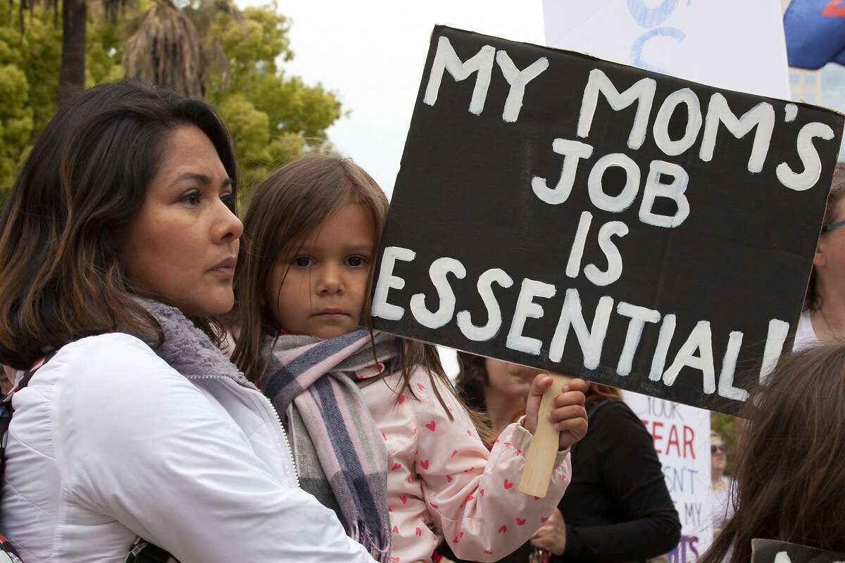 乔治娜Orante,抱着她的女儿索菲娅,4,在一次集会中,呼吁政府年底Gavin Newsom全职订单,在萨克拉门托,加利福尼亚州,星期一,2020年4月20日。数百人聚集在国会大厦要求纽森缓解限制和让人们重返工作岗位。Orante拥有一家美发沙龙在南加州和说,她将失去她的生意,如果她不能回去工作。(美联社照片/富Pedroncelli)我