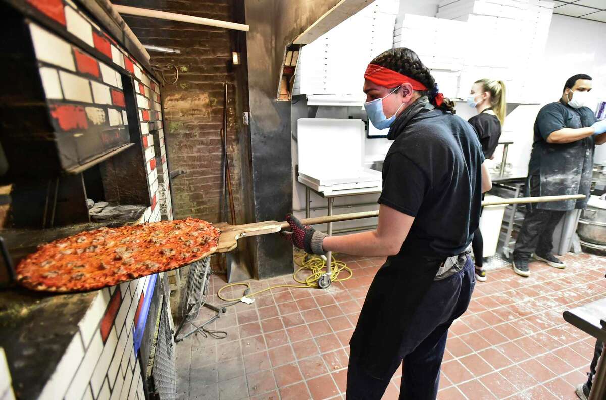 Brian Rodriguez, Sally's Apizza's baker moves a pizza around the coal-fired oven at the New Haven pizzeria in April 2020.