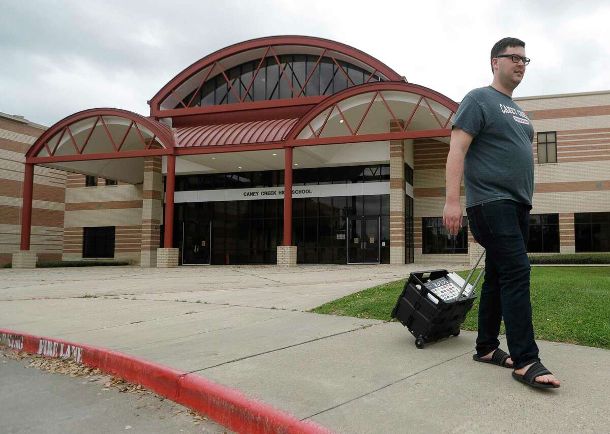 In this March photo, Caney Creek High School yearbook teacher Stephen Green wheels books to his car as he prepares to work for Conroe ISD from home. School districts across Houston are making contingency plans for when in-person classes might resume in 2020-21, which will largely depend on public health concerns tied to the novel coronavirus pandemic.