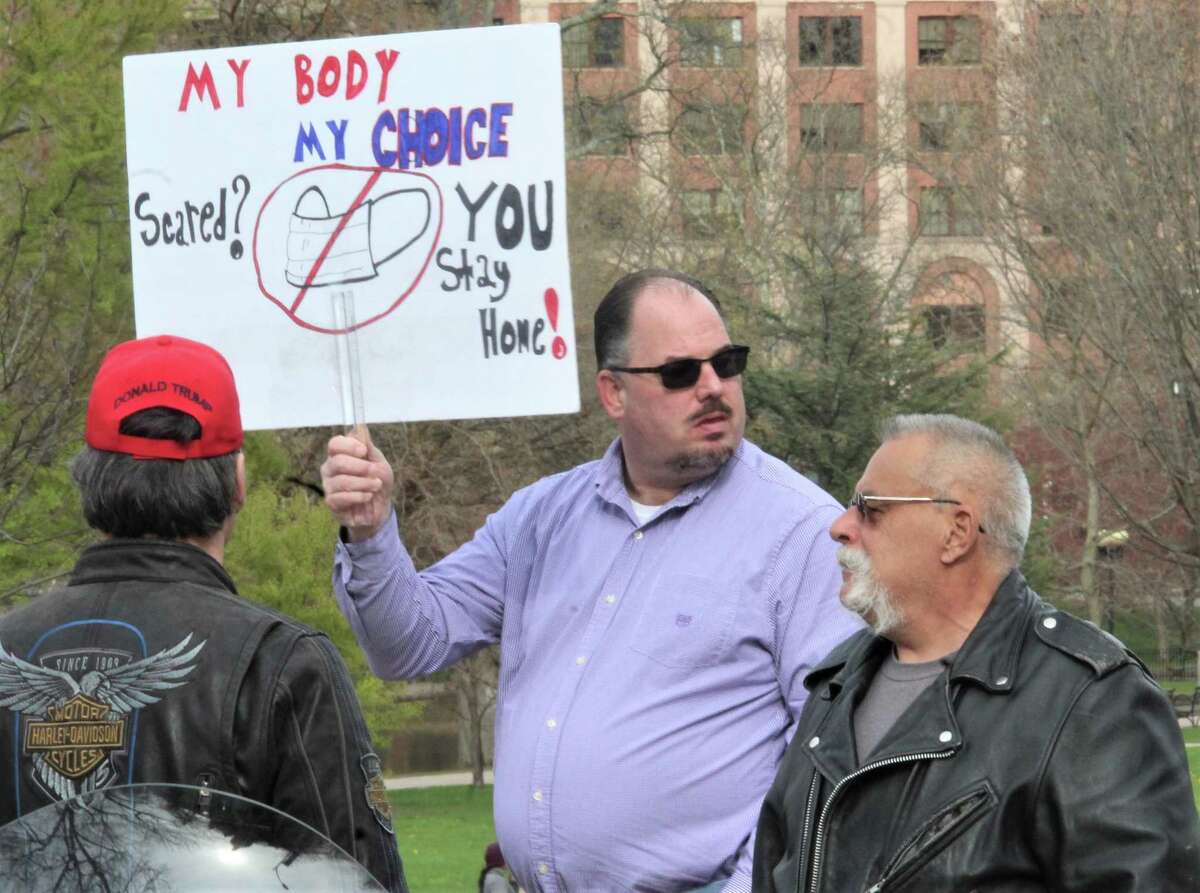 More than 1,000 people in about 300 vehicles circled the state Capitol and later the governor's residence in Hartford Monday, April 20, 2020, to protest the shutdown of the state for coronavirus. Many showed signs and wore hats and t-shirts in support of President Donald Trump. One lone counter-protester stood with a mask, and declined to give her name.