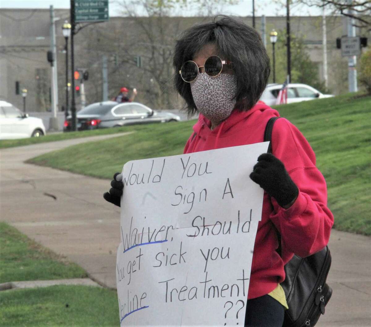 More than 1,000 people in about 300 vehicles circled the state Capitol and later the governor's residence in Hartford Monday, April 20, 2020, to protest the shutdown of the state for coronavirus. Many showed signs and wore hats and t-shirts in support of President Donald Trump. One lone counter-protester stood with a mask, and declined to give her name.