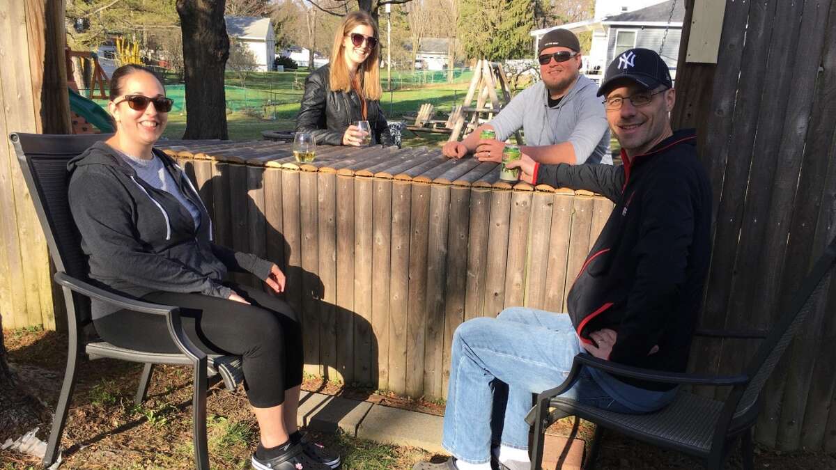 (l-r) Gina Smith, Katie Mahar, Charles Mahar and Thomas Smith enjoy a cocktail with their neighbors at their newly constructed bar in Latham. Charles Mahar and Thomas Smith converted the fence into a bar for about $15.