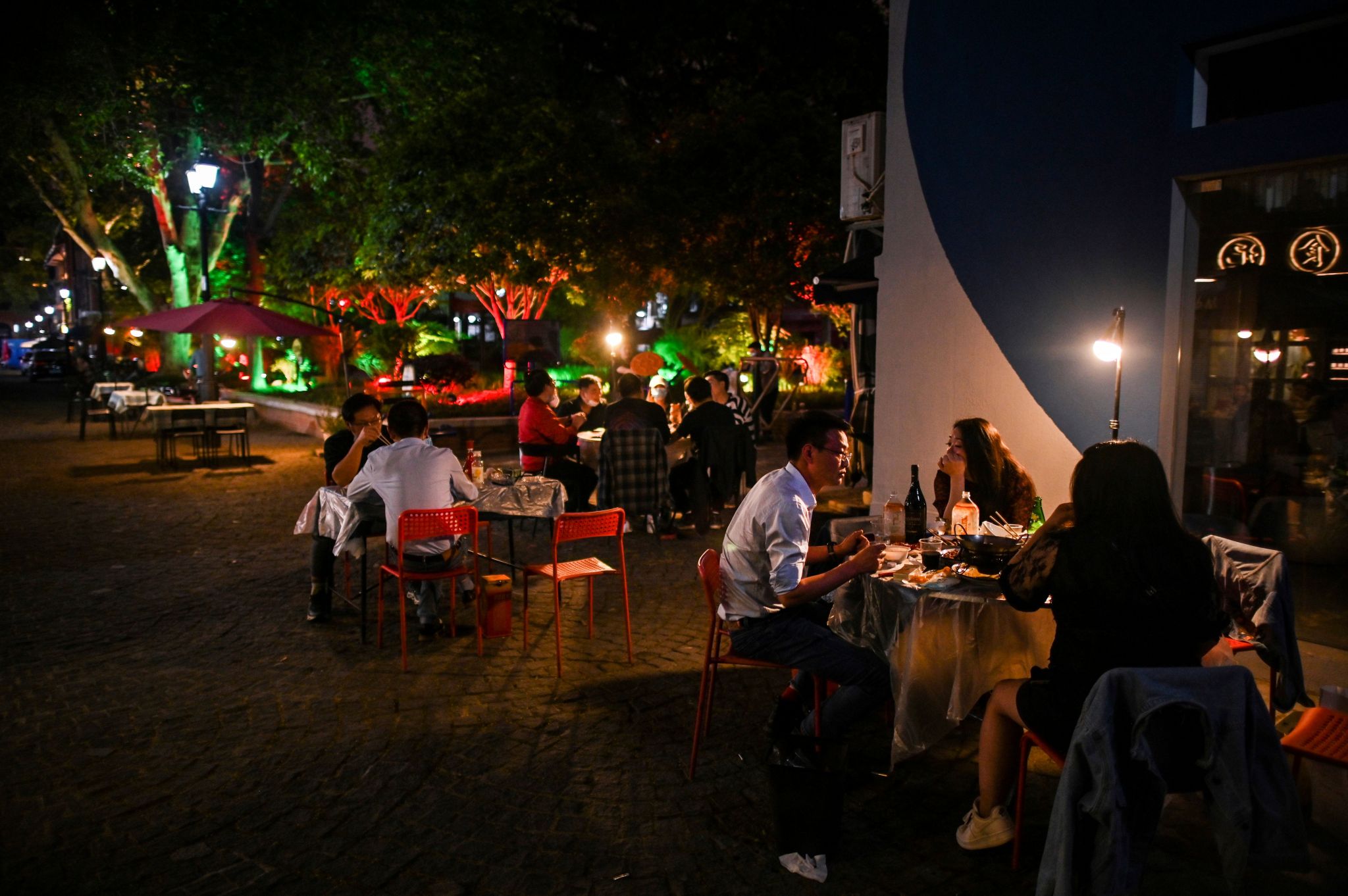 People eat outdoors next to a restaurant in Wuhan, in China's central Hubei province on April 16, 2020.