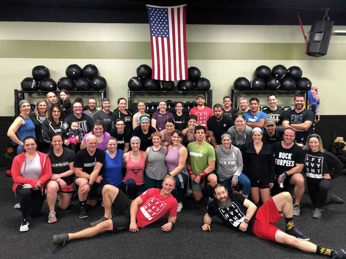 Athletes from Midland's CrossFit Jack Pine gather under the United States flag after a workout. The ownership team has distributed some 2,000 pounds of its own equipment to members so they participate in classes remotely during the gym's temporary closure. (Photo provided)