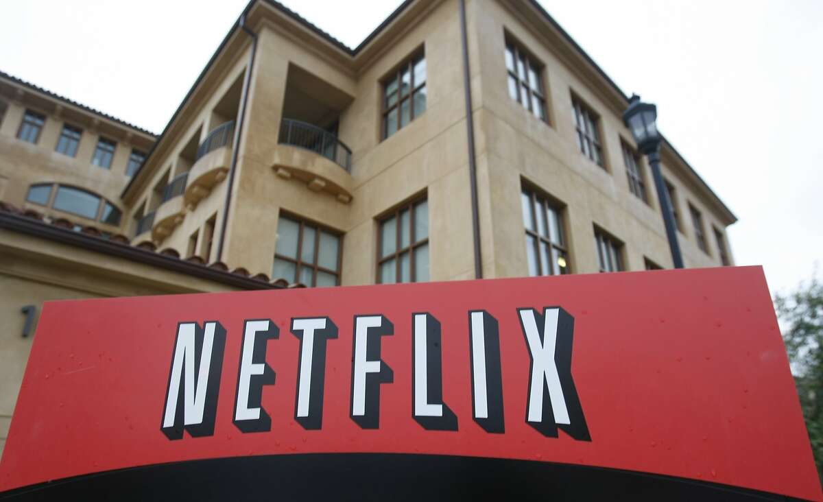 FILE - Streaming service Netflix said Thursday it's laying off 300 employees. This file photo shows the company logo and view of Netflix headquarters in Los Gatos, Calif.