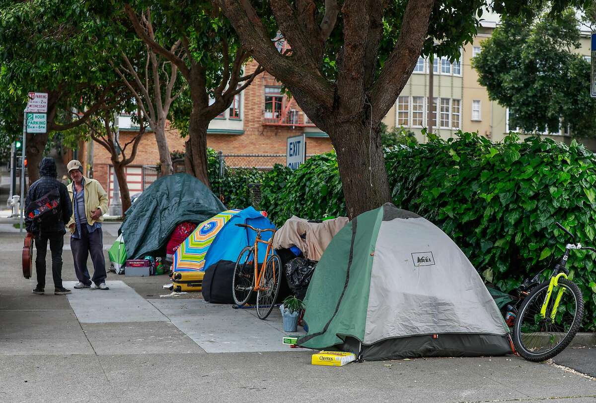 Homeless man Douglas Niemi (left) speaks to another homeless man outside a tent encampment on Broderick Street on Sunday, April 19, 2020 in San Francisco, California.