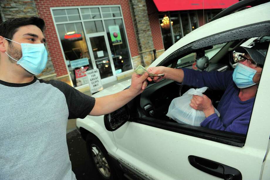 Matto Wine Bar employee Giancarlo Governale gets a tip from Stratford resident Teresa Reynolds after bringing a meal out to her during a free meal giveaway at the restaurant on Bridgeport Ave in Shelton, Conn., on Tuesday Apr. 21, 2020. As many as 100 meals were prepared today for the first come first serve event, which was to help anyone who needs a meal during the coronavirus pandemic. Photo: Christian Abraham, Hearst Connecticut Media / Connecticut Post