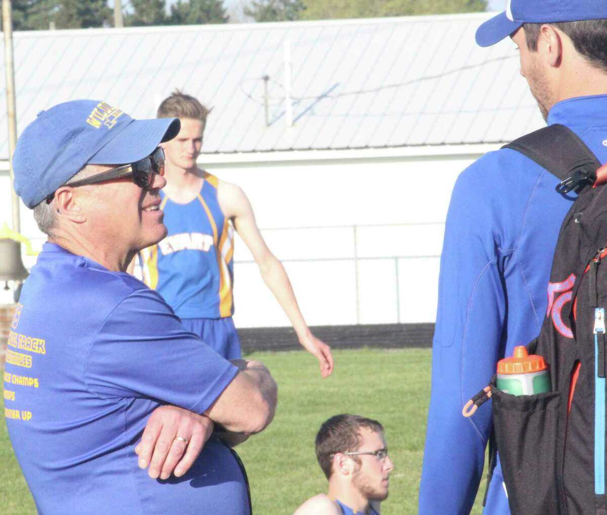 Evart's Dennis Peacock (left) has a discussion on the track sidelines during a meet last year. (Herald Review photo/John Raffel)