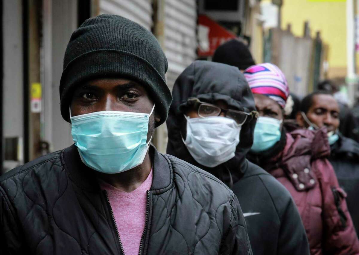 People wait for a distribution of masks and food from the Rev. Al Sharpton in the Harlem neighborhood of New York, after a new state mandate was issued requiring residents to wear face coverings in public due to COVID-19, Saturday, April 18, 2020. "Inner-city residents must follow this mandate to ensure public health and safety," said Sharpton. The latest Associated Press analysis of available data shows that nearly one-third of those who have died from the coronavirus are African American, even though blacks are only about 14% of the population. (AP Photo/Bebeto Matthews)