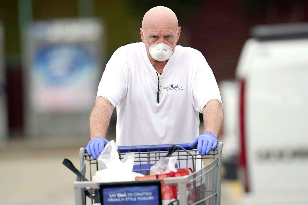 Gary Towler wears a face mask and gloves as he leaves a grocery store Wednesday, April 22, 2020, in Spring, Texas. Harris County Judge Lina Hidalgo is expected to announce an order, Wednesday, for residents to cover their faces in public to help slow the spread of COVID-19. (AP Photo/David J. Phillip)