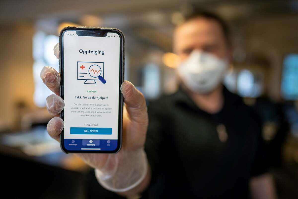 A man holds a smartphone showing a tracking and tracing app launched by the National Institute of Public Health to try to halt a return of the new coronavirus, on April 17, 2020 in Oslo. - Norway, one of the first European countries to begin lifting confinement measures, is launching a smartphone tracking and tracing app that has been developed to provide health authorities a better picture of the spread of COVID-19 and tell users if they have been in contact with the disease. (Photo by Heiko Junge / NTB Scanpix / AFP) / Norway OUT (Photo by HEIKO JUNGE/NTB Scanpix/AFP via Getty Images)
