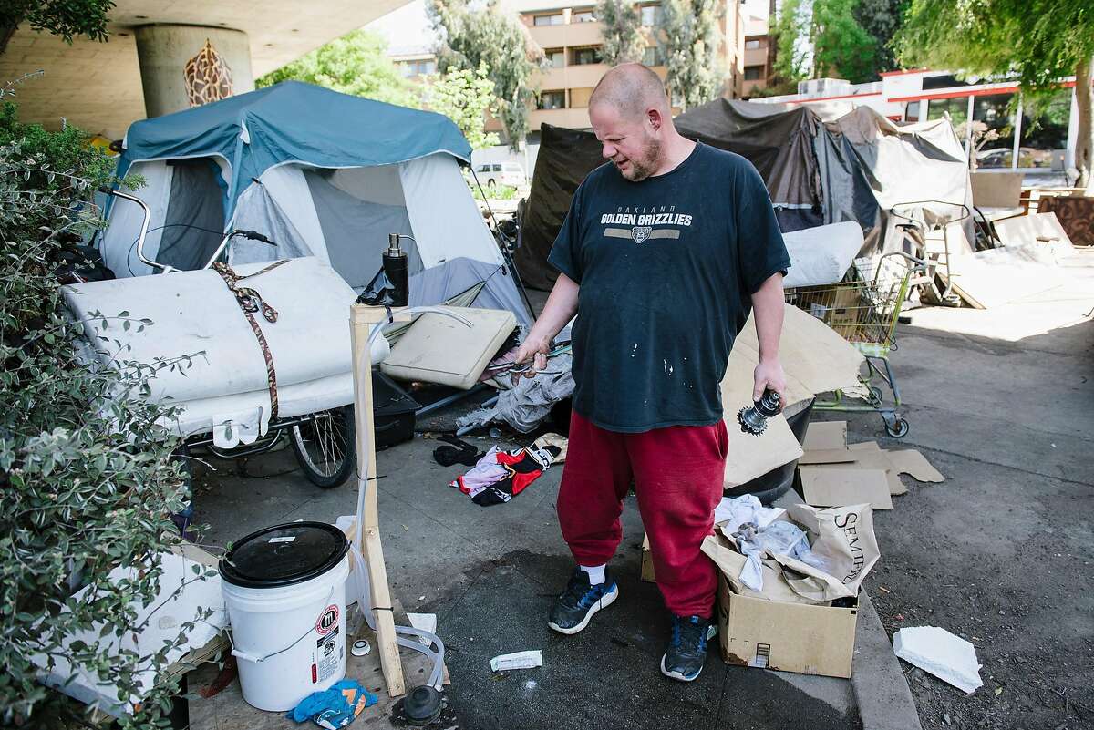 Nick Becker, points out a soap and water washing station that was donated by nearby neighbors at the homeless encampment underneath Interstate 580 where he has lived for the last 2 1/2 years, in Oakland, Calif, on Friday, April 22, 2020. Nick said that county officials that have visited the encampment have only offered quarantine shelter beds to people that are presenting symptoms of Covid-19.