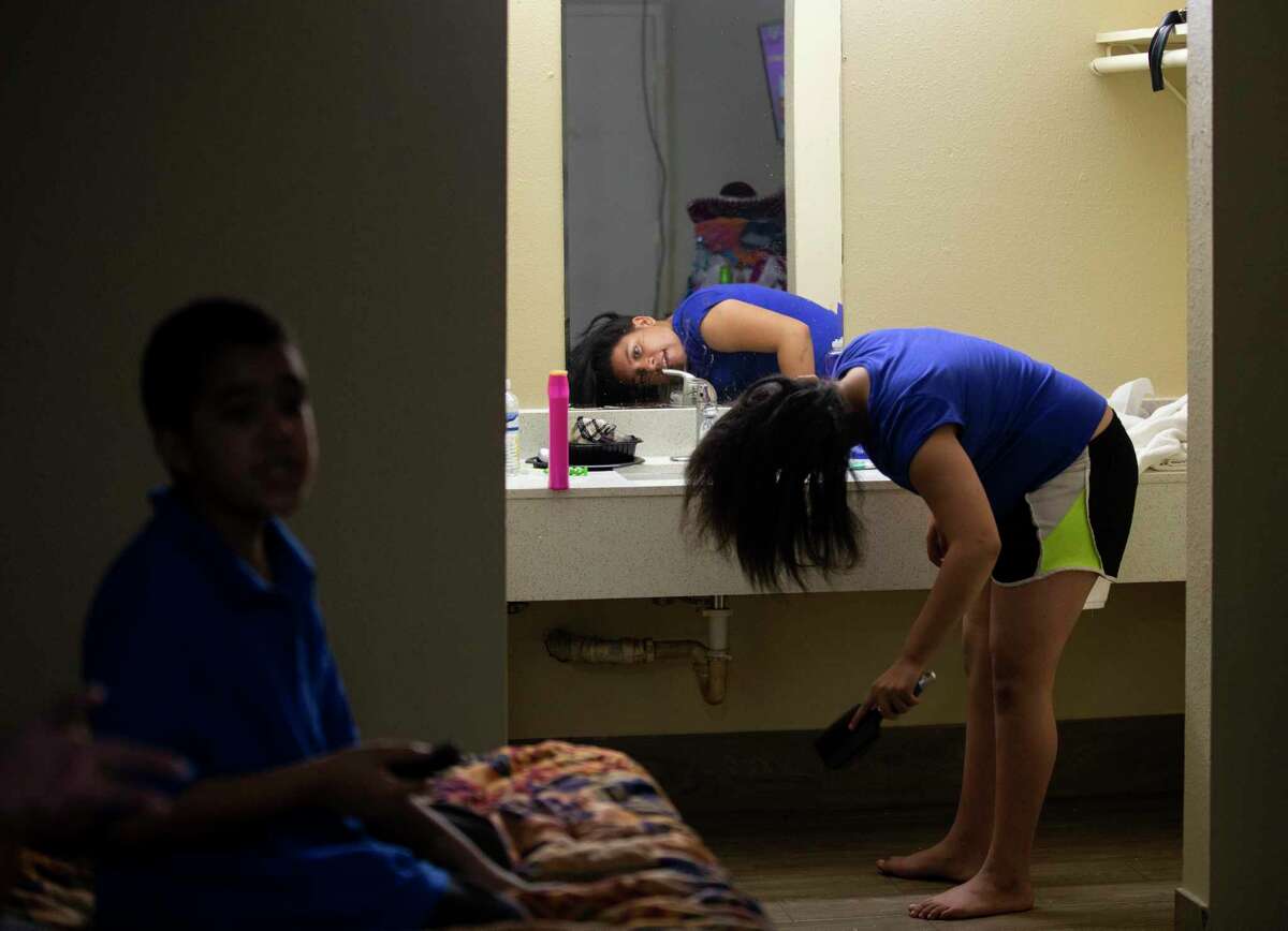La'Keisha Lawrence, 11, brushes her hair as her 6-year-old brother Na'Kahi looks for something to watch on YouTube.