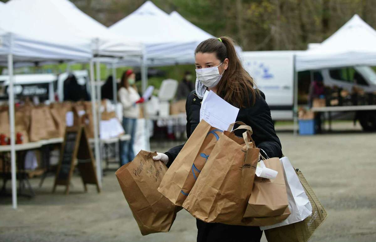 Customers pick up their groceries at the Westport Farmer's MarketThursday, April 23, 2020, in Westport, Conn. The market has gone digital where customers call and give their orders and are given a pickup time and the order is prepared without contact.