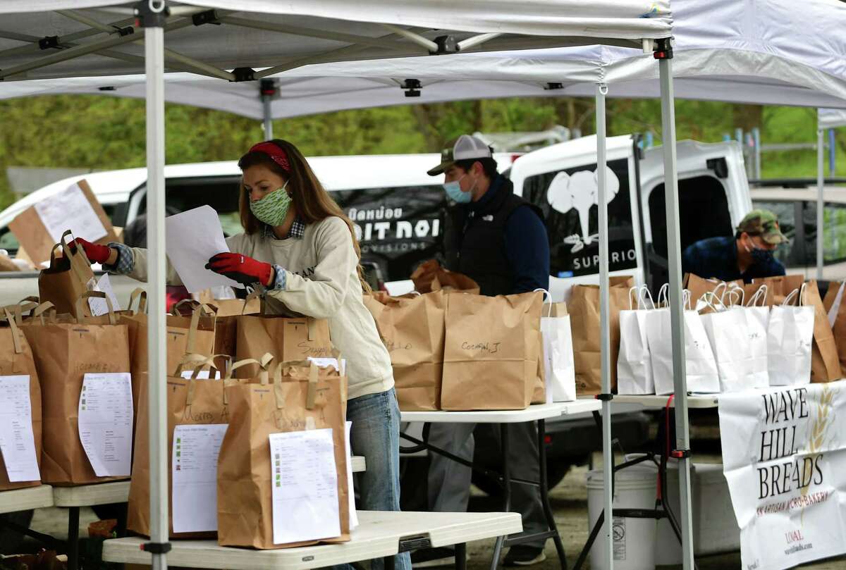 Vendors ready the food as customers pick up their groceries at the Westport Farmer's MarketThursday, April 23, 2020, in Westport, Conn. The market has gone digital where customers call and give their orders and are given a pickup time and the order is prepared without contact.