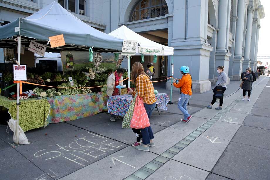 People practice social distancing as they wait in line to purchase produce from a vendor during the Ferry Plaza Farmers Market on April 21, 2020 in San Francisco, California. Photo: Justin Sullivan/Getty Images / 2020 Getty Images