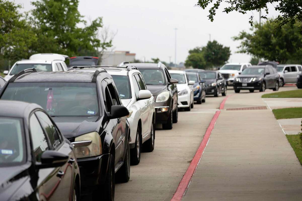Vehicles line up as they await their turn to receive receive during a weekly mega food distribution event at the Houston Premium Outlets in Cypress, Wednesday, April 22, 2020. The vehicle line began forming early in the morning and spanned approximately 2.5 miles long.
