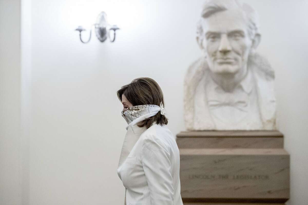 A bust of President Abraham Lincoln is visible behind House Speaker Nancy Pelosi of Calif. as she arrives on Capitol Hill, Thursday, April 23, 2020, in Washington. (AP Photo/Andrew Harnik)
