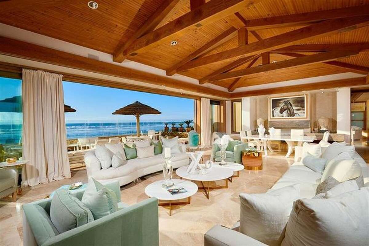 Living room. The elegant residence comes with 120 feet of private ocean frontage. Wide windows throughout the living spaces open to the back patio, offering a seamless flow between the indoor and outdoor spaces. The large patio also provides awe-inspiring vistas of the Pacific Ocean.