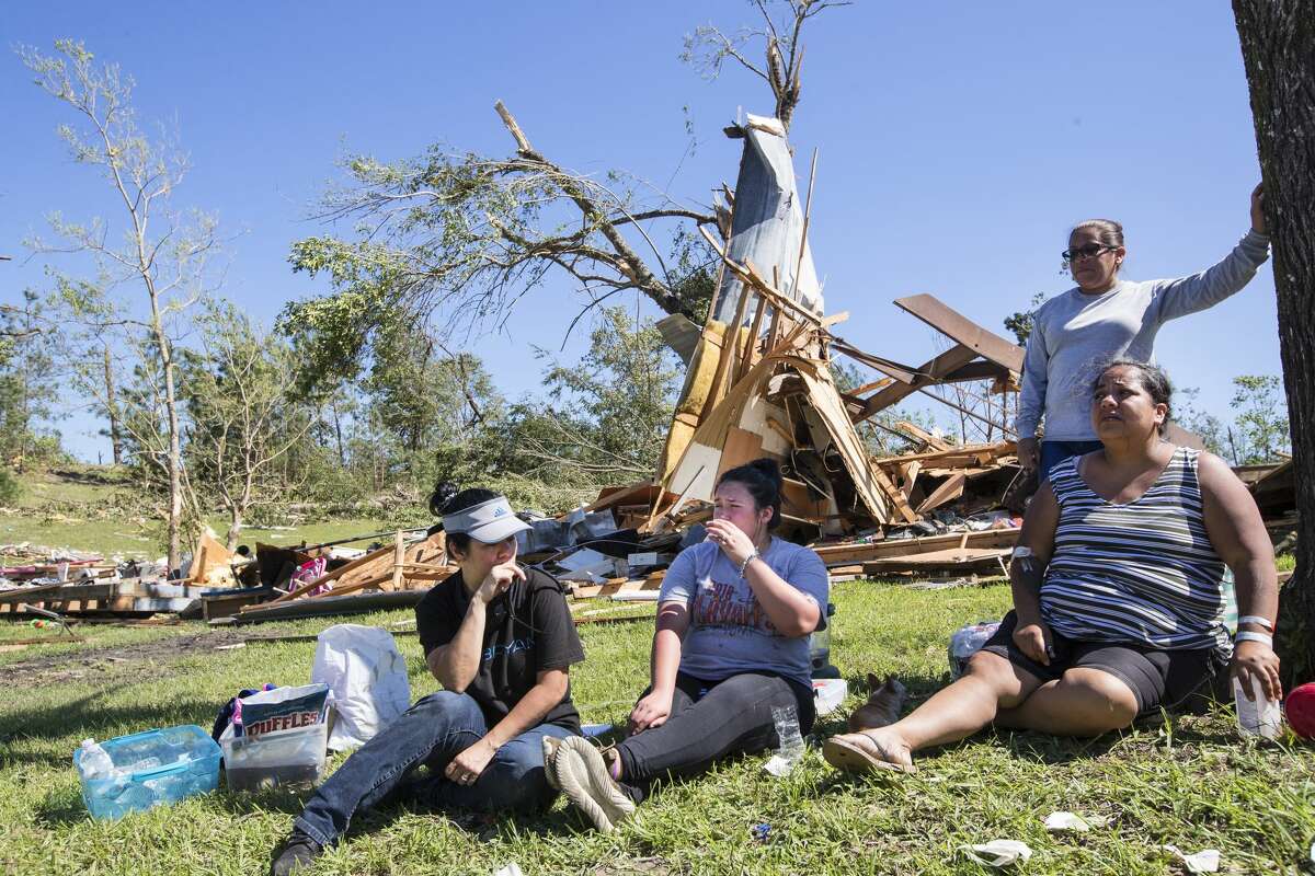 Brenda Avila, left, Janet Flores, Mayra Jimenez and Maria Jimenez, standing, take a break from searching through Mayra Jimenez' destroyed home on Thursday, April 23, 2020, after a tornado ripped through the area Wednesday night in Onalaska, Texas. At least three people were killed and more than 30 people were injured when a tornado ripped through the small East Texas city, about 85 miles north of Houston.