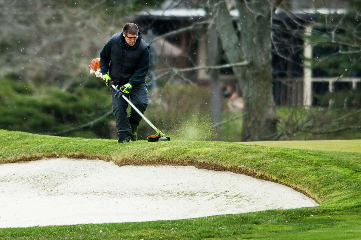 FILE — Sean DeShone, a bunker specialist at Midland Country Club, performs maintenance Wednesday, April 22, 2020 on the golf course. (Katy Kildee/kkildee@mdn.net)