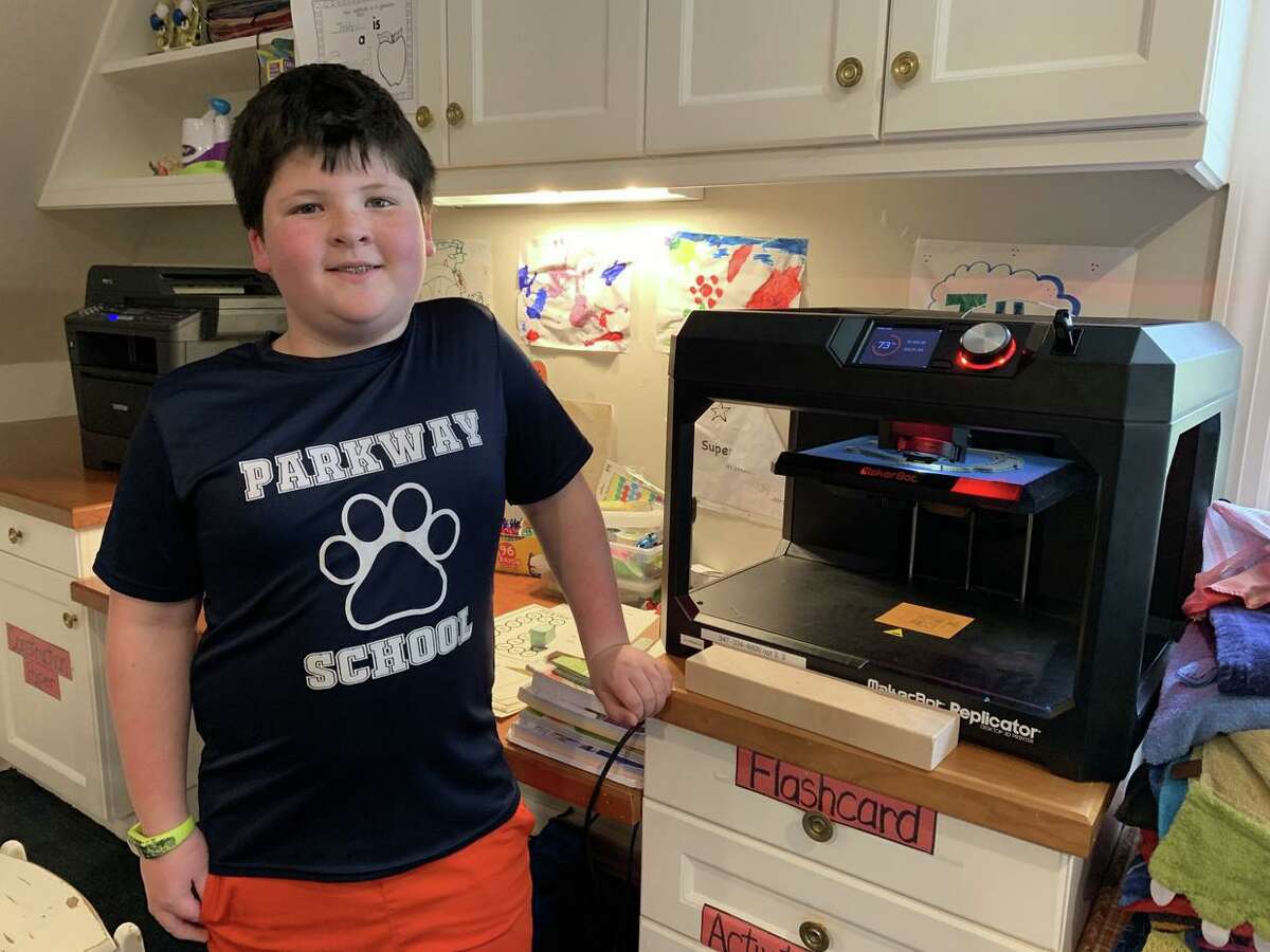 Parkway School fourth grader Teddy Curreri poses next to his 3D printer, which he used to print shields for hospital workers at Stamford Hospital. PTA Vice President Meredith Curreri and his mother supplied the plastic through her employer, Synchrony, and its #GearUp program.