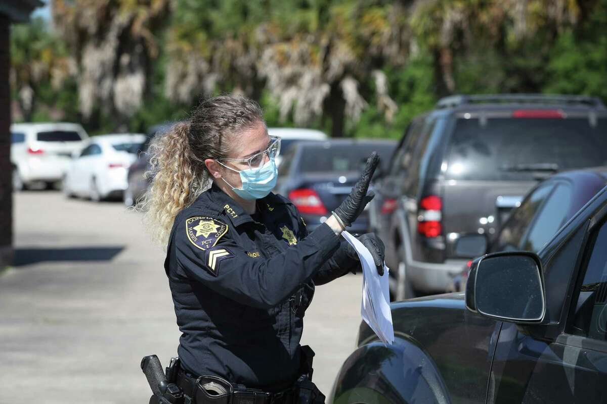 Harris County Constable Corporal Toni Mascione handed out numbers for vehicles that received masks and gloves along with some nonperishable food supplies during Constable Alan Rosen COVID-19 Drive-Thru Thursday, April 23, 2020, in Houston. Rosen said that they handed out over a 1,000 masks and gloves along with food to many in need. Some cars lined up as early as 6 a.m. for the give away.