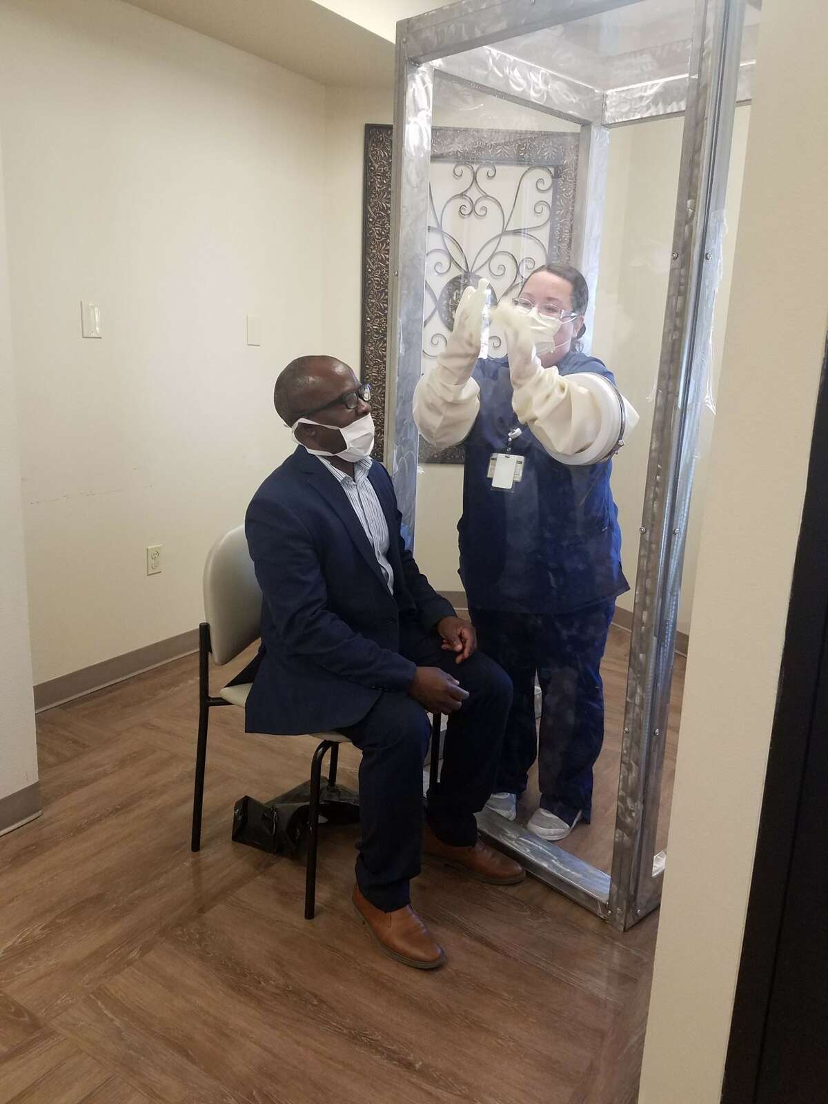 Dean of engineering George Nnanna displays how the plexiglass booth for coronavirus testing works with ORMC employee Connie Benitez at Odessa Regional Medical Center.