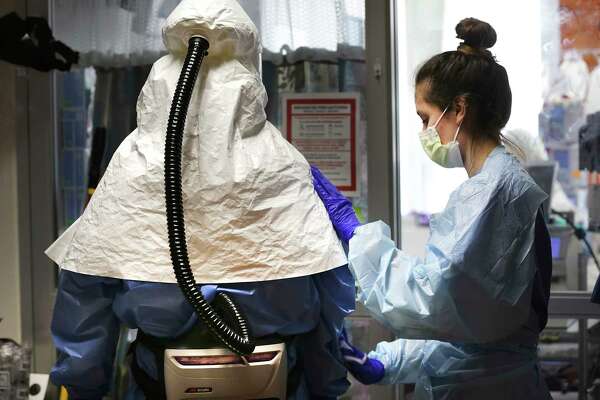 A Methodist Hospital nurse, right, wipes down a doctor as part of the hospital’s sanitization procedures.