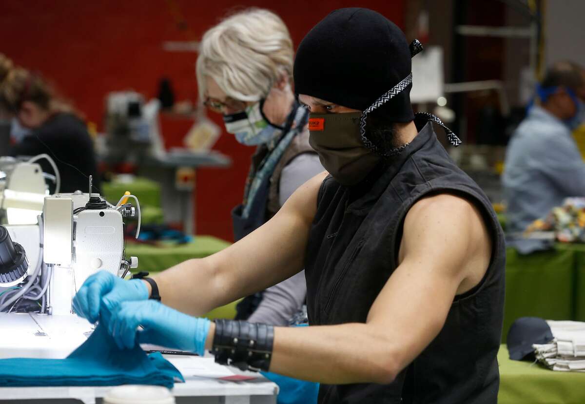 Micah Cash and Deborah Keiser (left) sew face masks using t-shirts donated by pro sports teams at the Timbuk2 factory in San Francisco, Calif. on Tuesday, April 21, 2020. Timbuk2 is suspending production of its popular messenger bags and is teaming up with NBC Sports Bay Area and California to manufacture face masks for medical workers from surplus apparel donated by seven local professional sports teams.