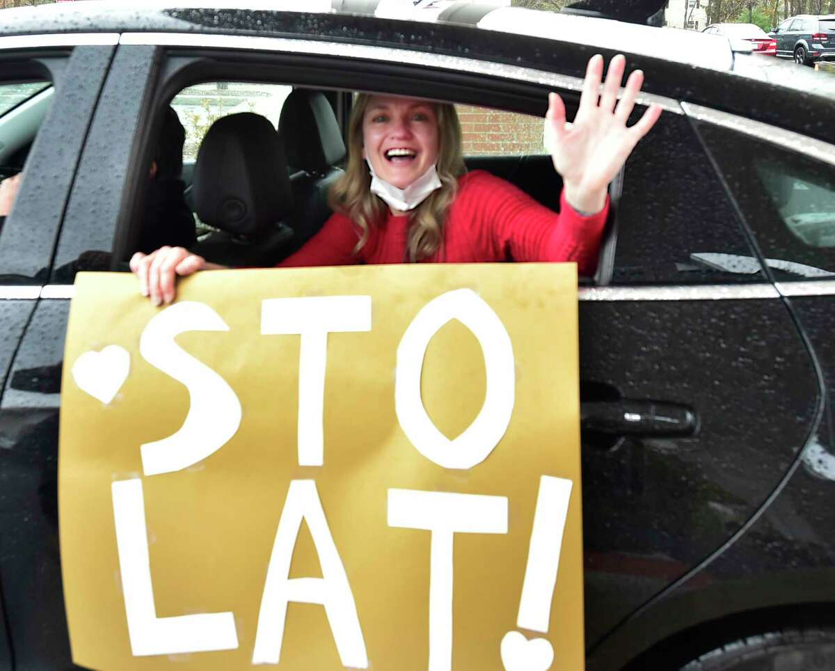 North Haven, Connecticut - Friday, April 24, 2020: Cathy DellaValle of Haven, holds a sign "Sto lat", the name of a Polish song that is sung to express good wishes, good health and long life to a person during a celebratory procession Friday honoring her father Edward Otremba Sr., 100, a resident at The Landing of North Haven assisted living facility, during his centennial birthday party using social distancing with a community car parade that included a North Haven Fire Department truck, the presentation of a birthday cake, and birthday songs in English and Polish. Ed?•s family was planning on a huge celebration at the community with friends and family but it had to canceled because of the Coronavirus / Covid-19 pandemic