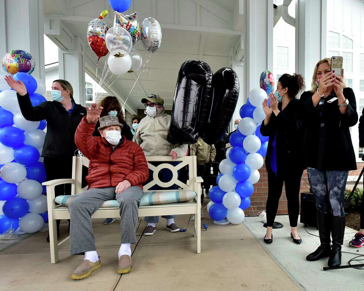 North Haven, Connecticut - Friday, April 24, 2020: Edward Otremba Sr., a resident at The Landing of North Haven assisted living facility, seated, left, gets a birthday celebration at 100-years-old Friday using social distancing with a community car parade that included a North Haven Fire Department truck, the presentation of a birthday cake, and birthday songs in English and Polish. Ed's family was planning on a huge celebration at the community with friends and family but it had to canceled because of the Coronavirus / Covid-19 pandemic