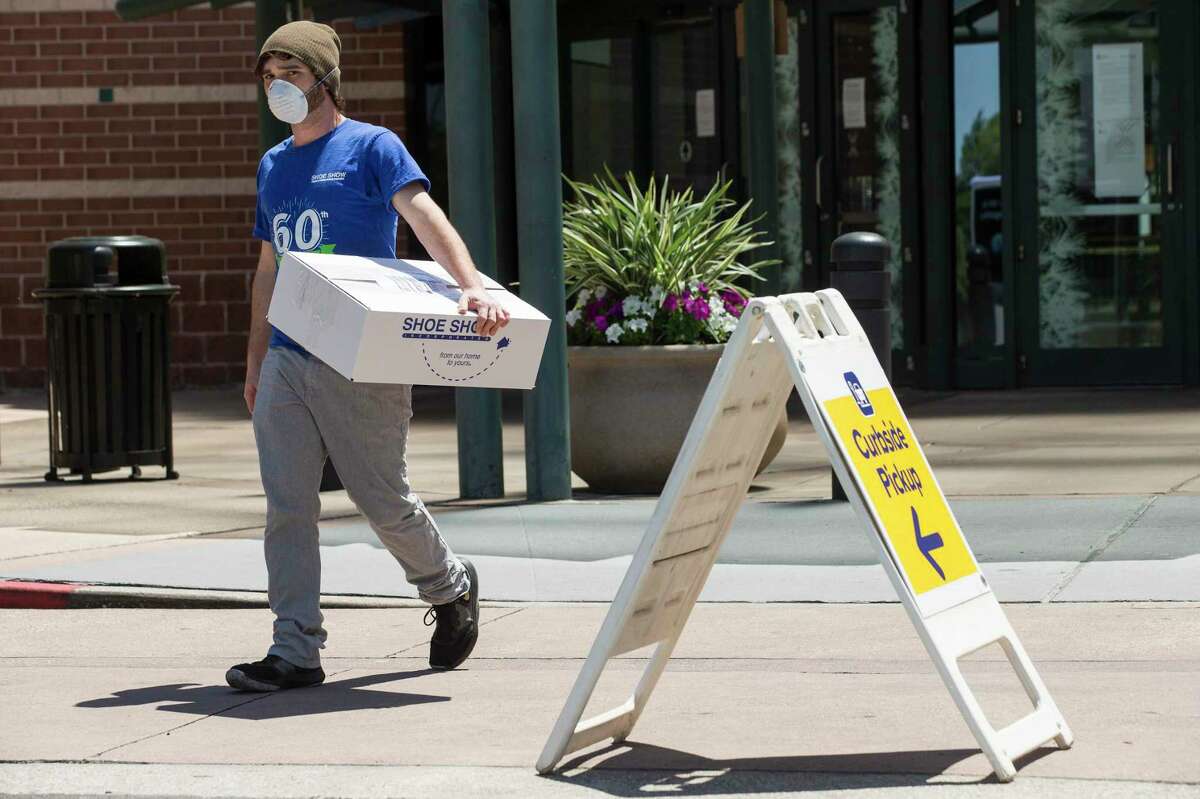 Will Nolan carries packages from Shoe Show out the door of the Woodlands Mall while taking them to be delivered to customers on Friday, April 24, 2020 in The Woodlands. Retail shops are beginning to re-open after being shut down because of the coronavirus pandemic. Many are beginning to offer curbside delivery of items outside the mall.