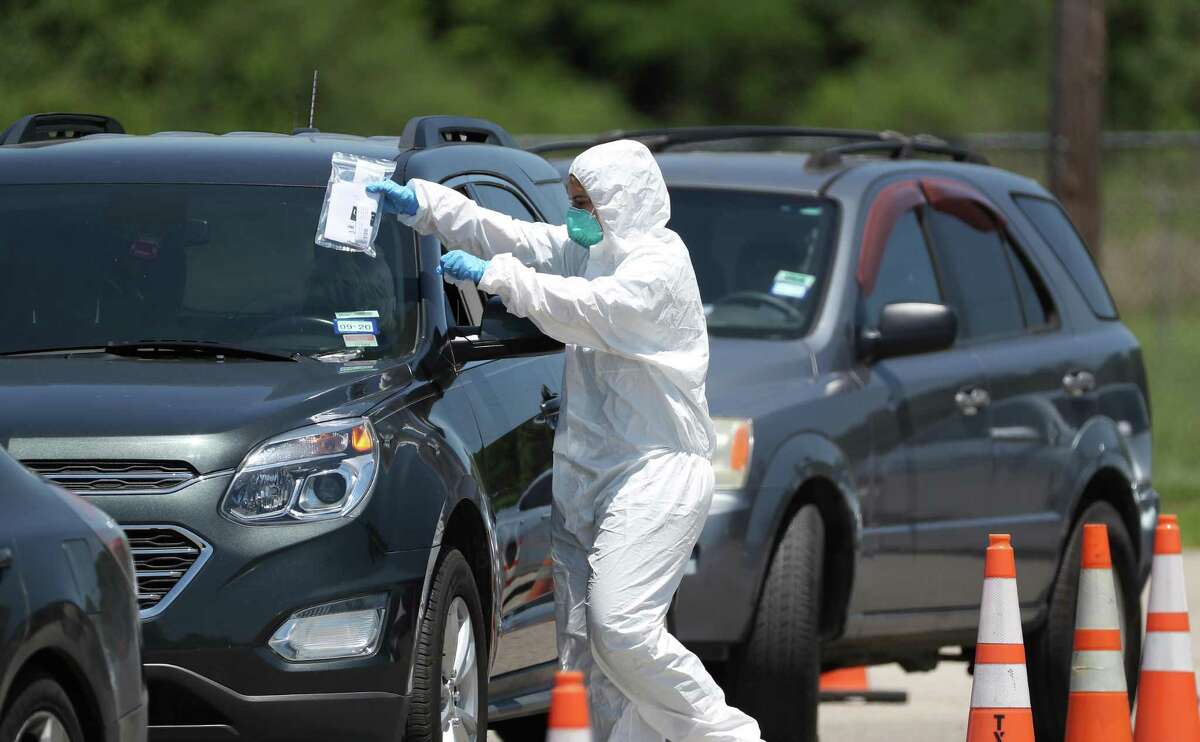 A worker places information on the windshield of a person wanting to get tested at a COVID-19 testing site located at 7525 Tidwell Friday, April 24, 2020, in Houston.