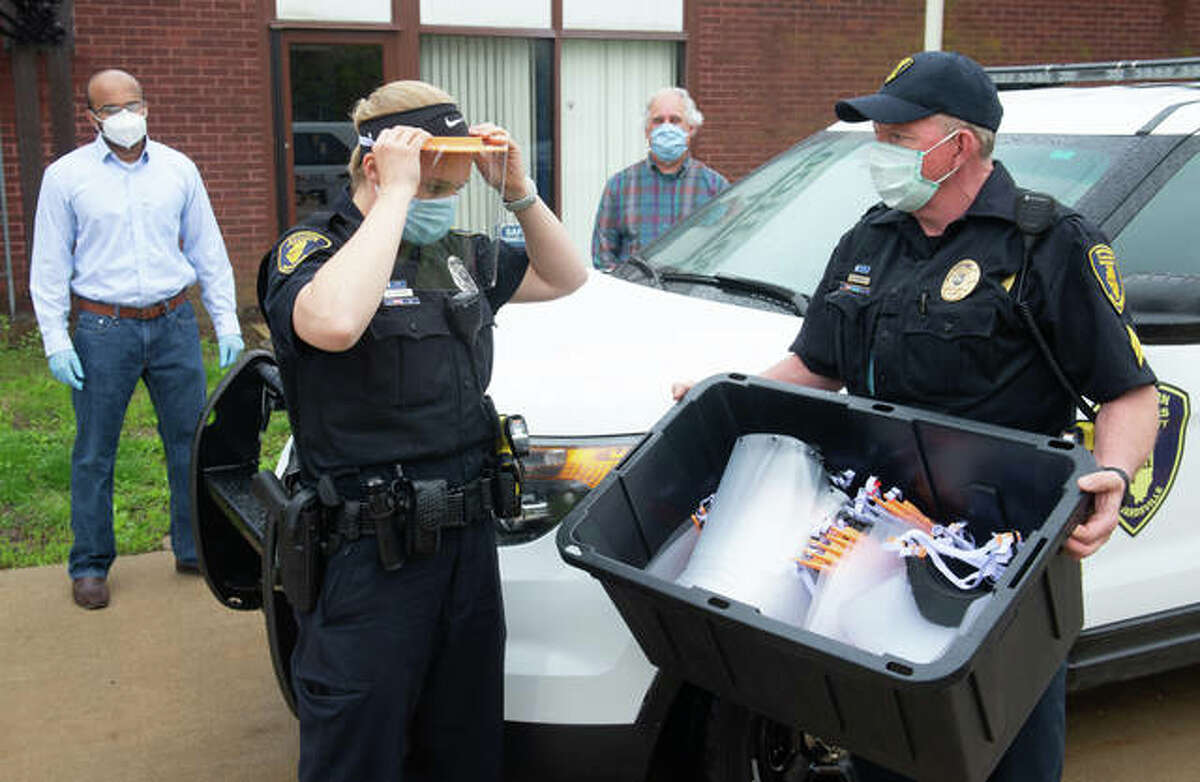 SIUE Police Officer Katie Kircher, left, tries on a face shield, as Sergeant Dan Murphy, right, watches. School of Engineering’s Jagath Gunasekera and Brent Vaughn delivered the personal protective equipment.